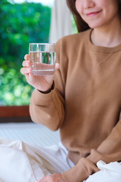 Vertical closeup image of a woman holding a glass of drinking water