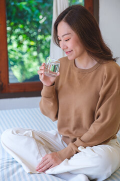 Vertical portrait image of a woman holding and drinking water at home