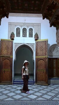Marrakech, morocco. August 10, 2026. Caucasian woman with a hat and backpack visiting the bahia palace. Detailed moroccan arabesque architecture with zellij tilework and carved wooden doors
