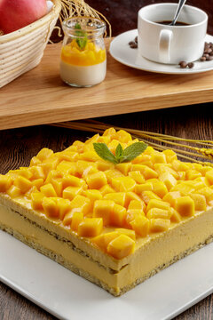 A three-tiered mango cream cake is placed on a wood-grain base.