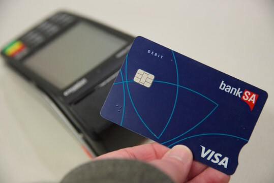 Semaphore, South Australia - July 22 2026: hand holding a payment card near a retail point of sale machine for transaction