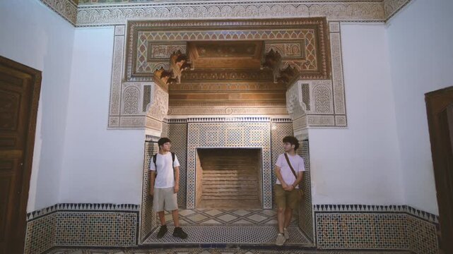 Marrakech, morocco. August 10, 2026. Two young male travelers standing inside a room of the bahia palace in marrakech, morocco, admiring the intricate zellij mosaics