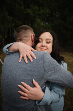 Tender portrait of an expectant mother embracing her husband closely outdoors in a forest during their twin pregnancy photoshoot.