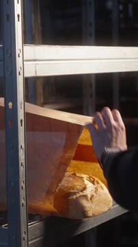 Bakery Worker Placing Fresh Bread into Protective Paper Packaging