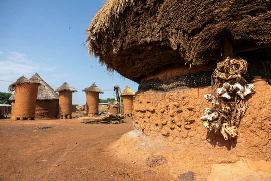 Animal skulls hang beside adobe granaries topped with thatched roofs in a village, Savanes district, Niofoin, Ivory Coast