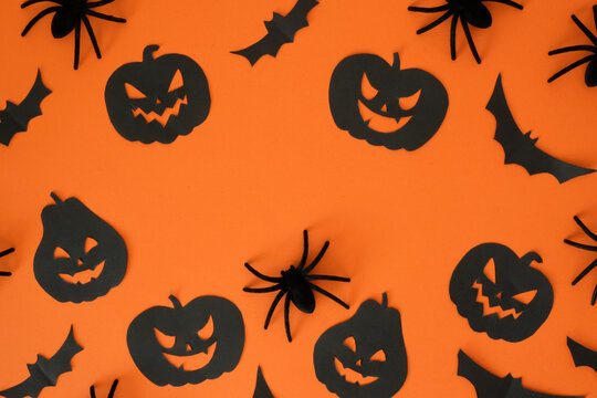 Black jack-o'-lanterns, spiders, bats shapes and place for text on an orange background