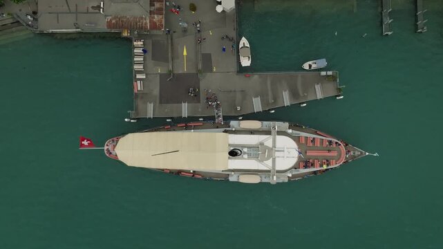 Top down drone view of historic steamer departing lakeside pier Lake Lucerne Switzerland