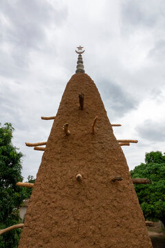 Three bell-shaped ceramic caps top pinnacles framed by lush mango foliage at the 17th-century Sudano-Sahelian mosque, Savanes district, Kouto, Ivory Coast