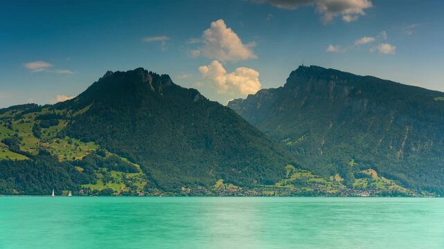 Dramatic timelapse of clouds moving over Lake Thun and Swiss Alps peaks Niesen and Stockhorn on a sunny summer day in Switzerland