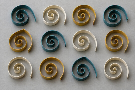 Paper quilling, raised spiral coils in a teal and ivory arrangement