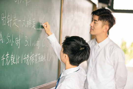 Teacher Helping Student Solve Math Problems at Classroom Blackboard