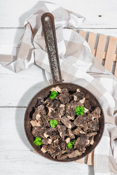 Raw black morel mushrooms with fresh parsley. Vegan ingredient for cooking healthy food