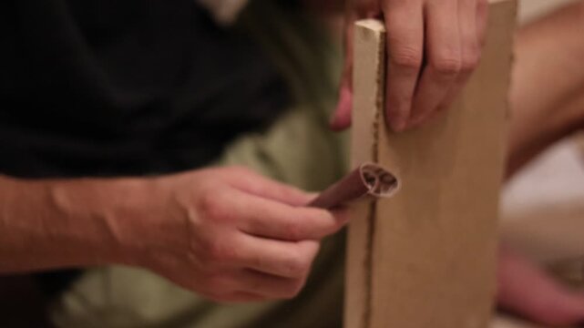 Craftsman sanding a wooden frame with sandpaper for smooth surface finishing during carpentry work