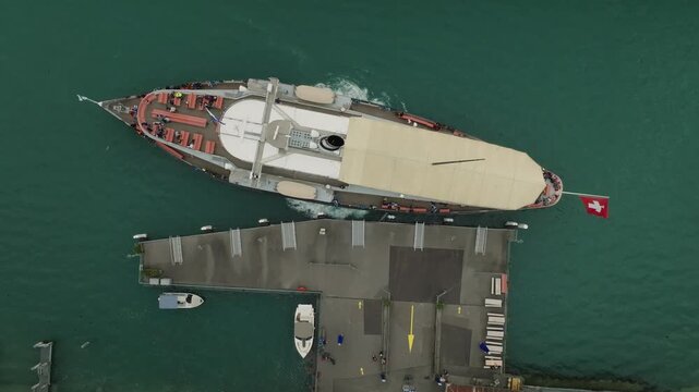 Top down drone view of historic steamer departing lakeside pier Lake Lucerne Switzerland