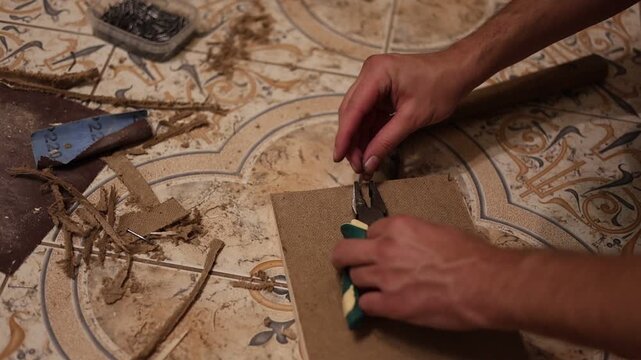 Craftsman removing staples and nails from a wooden board during vintage furniture restoration or repair work