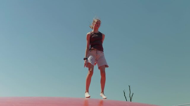 Girl does the splits while jumping the sky in the background slow motion