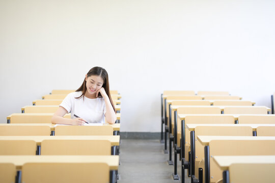 Happy student studying alone in a bright empty classroom