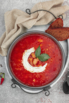 Traditional Ukrainian borscht with sour cream and bay leaves in a bowl, with dark rye bread slices