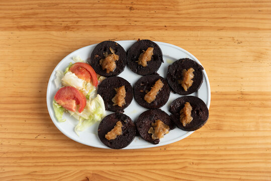 Plate of spicy black pudding from Zamora with caramelized onion and salad.