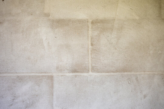Exterior block wall covered with adhesive mortar and reinforcing mesh, prepared for primer and final facade plaster during house construction and renovation.