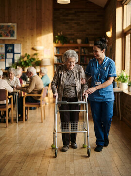 Caregiver named Sarah walking alongside an elderly woman using a rolling walker
