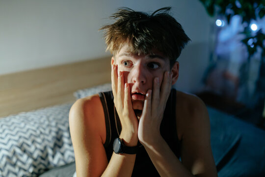 Close up of a restless teenage boy experiencing a panic attack at night.