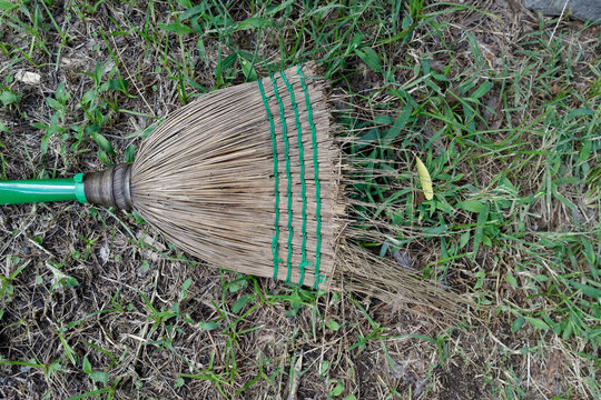 A used shabby broom across a patch of green grass.