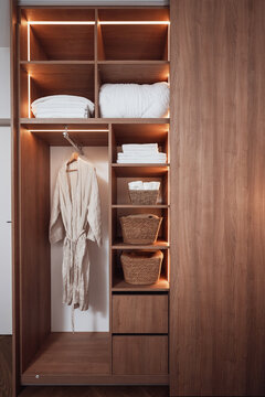 Open wardrobe with robe, towels, and beddings in baskets