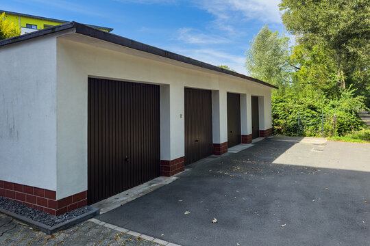 Four brown garage doors in a quiet outdoor space