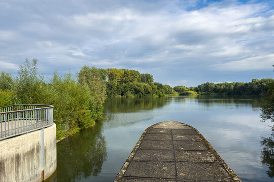 View of a calm river surrounded by green trees on a cloudy day