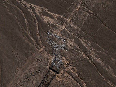 aerial view of high voltage power transmission tower in desert landscape