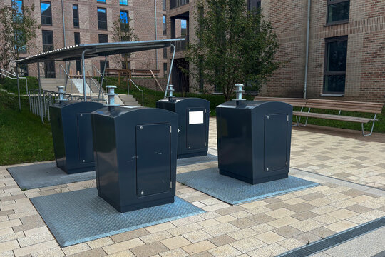 Four recycling boxes arranged in a courtyard area of a building