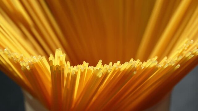 Rotating close-up of dry spaghetti pasta ends spread out with warm lighting.