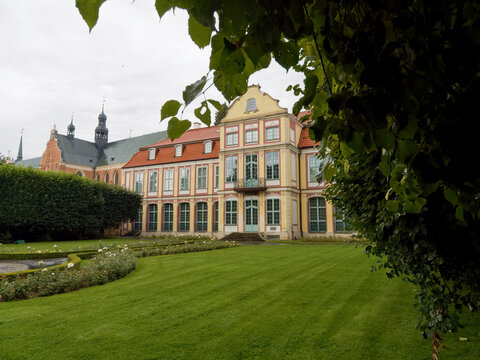 Building with green lawn and hedges near historical structure in an open space during cloudy day