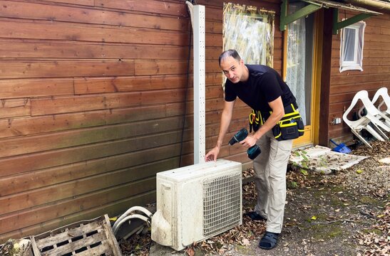 Technician servicing outdoor heat pump unit with tools beside residential house. Concept of HVAC maintenance home climate control and energy efficient heating and cooling