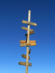 Rustic wooden directional signpost with destination arrows against clear blue sky © shotbydani