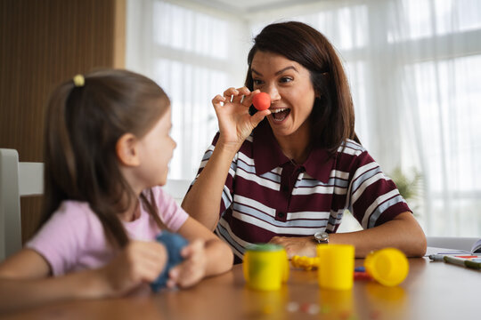 Mother and daughter playing with modeling clay at home