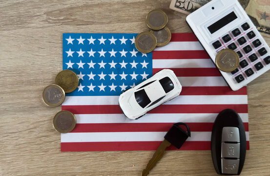 american flag displayed on desk with toy car, calculator, key, and coins in neutral top-down perspective, red, white, blue, gold colors, business, finance, travel contexts.