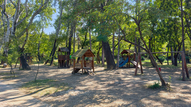 Empty wooden playground structures inviting children to play and imagine in a lush green park, representing outdoor fun, childhood memories, and family leisure activities