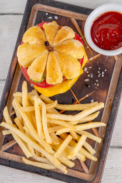 Pumpkin shaped burger. Tasty cheeseburger for Thanksgiving or Halloween party, made with pumpkin shaped bread bun, meat cutlets, melted cheese and fresh vegetables, with ketchup sauce, french fries