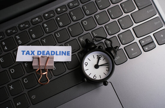 A note reading "TAX DEADLINE" is clipped to the top of the keyboard with a paperclip as a reminder that the tax payment deadline is approaching.