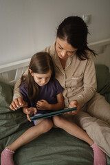 Mother and daughter using tablet before bedtime © Miljan Živković