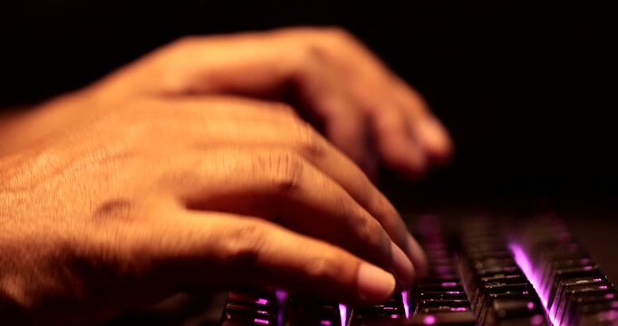 Close-Up of Man Hands Typing on Backlit RGB Mechanical Gaming Keyboard in Dark Office