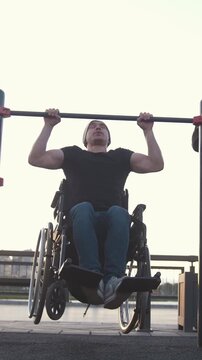 Disabled man in wheelchair pulled up on the bar next to young woman outdoors