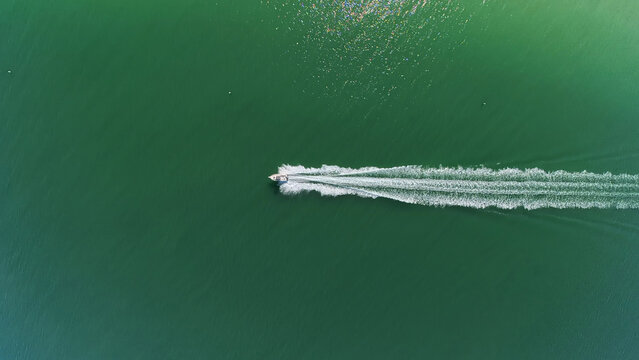 Travel and Recreation: Directly Above Aerial View of Powerboat Speeding Across Green Waters Leaving White Water Trail in St. Pete Beach, Florida