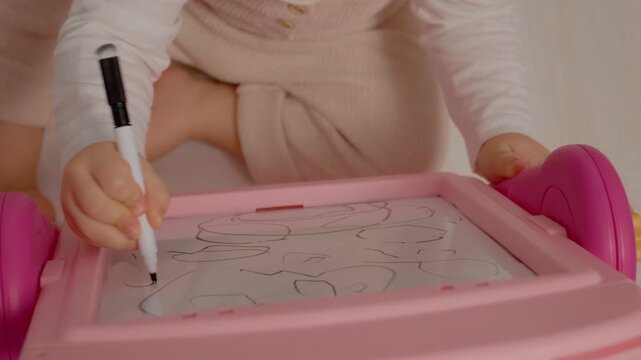 A child draws and erases on a blackboard, showcasing creativity and imagination. The close-up highlights small hands in action, focusing on the drawing process.