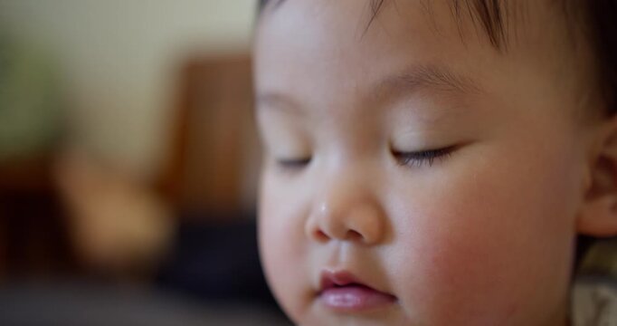 An innocent Asian toddler looks directly at the camera with curiosity, a soulful close-up portrait representing childhood development, hope, and the future from home.