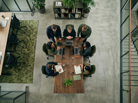Seven colleagues gathered around a dark wood table in a modern bright office
