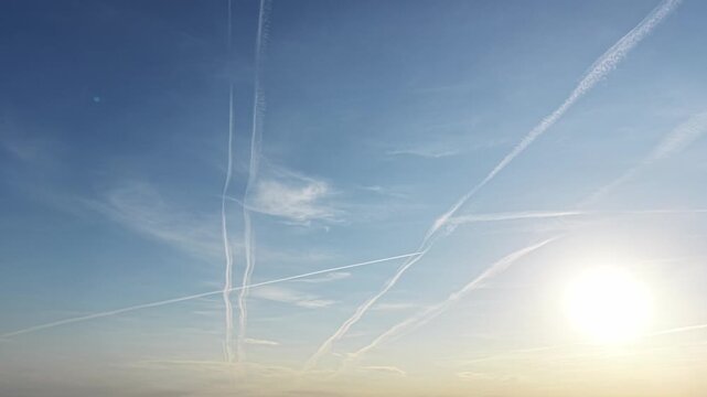 Warm light illuminating clouds and contrails at dusk