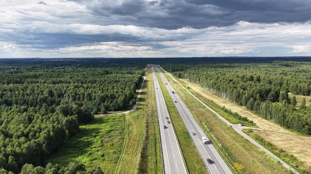 High-angle aerial view of a highway with motion-blurred traffic passing through forest and farmland